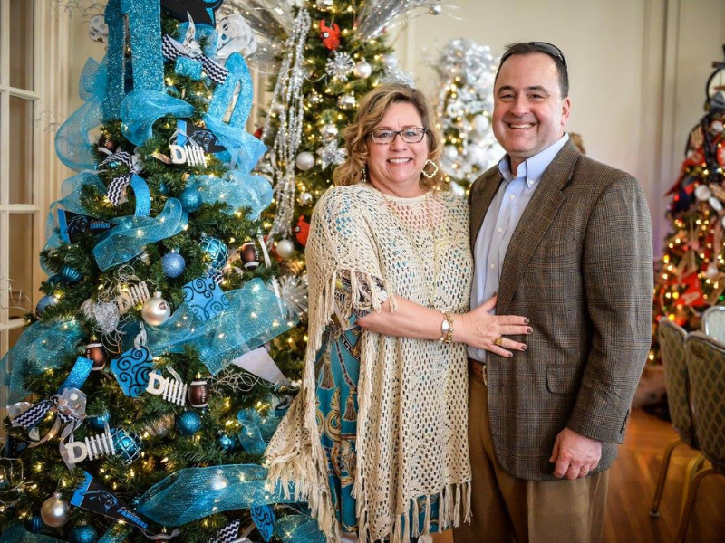 Couple standing beside Christmas tree with blue ribbon