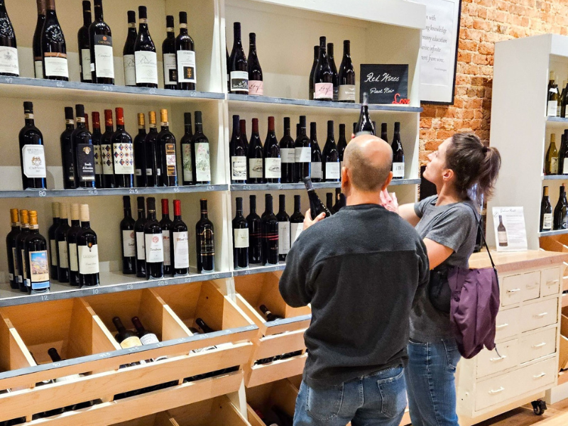 Couple browsing wine selection on display shelving.
