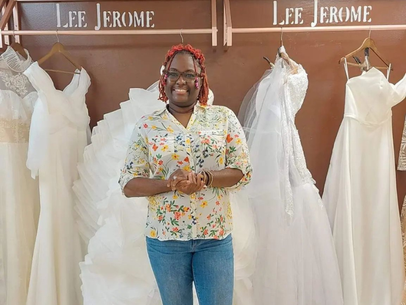 Owner of Mahogany Brown Bridal standing in front of wedding gowns 